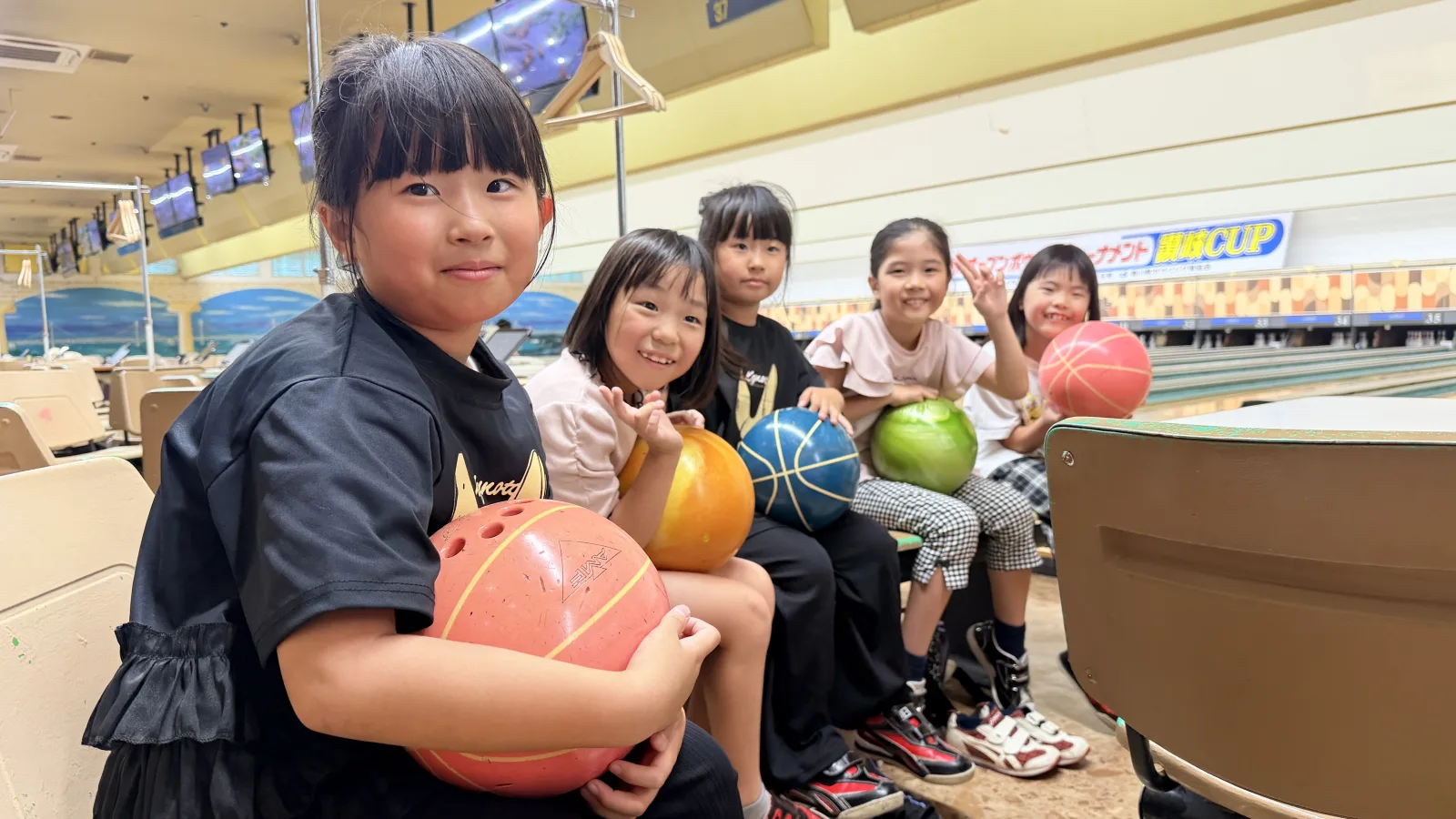 ボウリングを楽しむクローネ学園の小学生たち。カラフルなボールを手に笑顔を見せている。