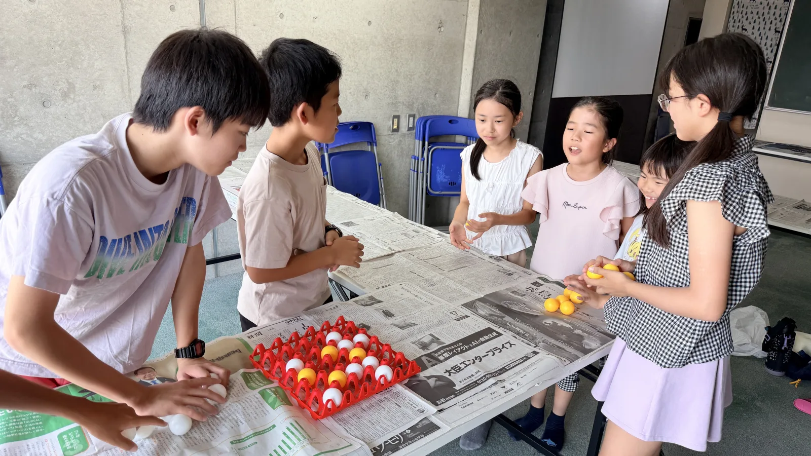 会場の設営を終えて、机を囲んでひと息つくクローネ学園の塾生スタッフたち。